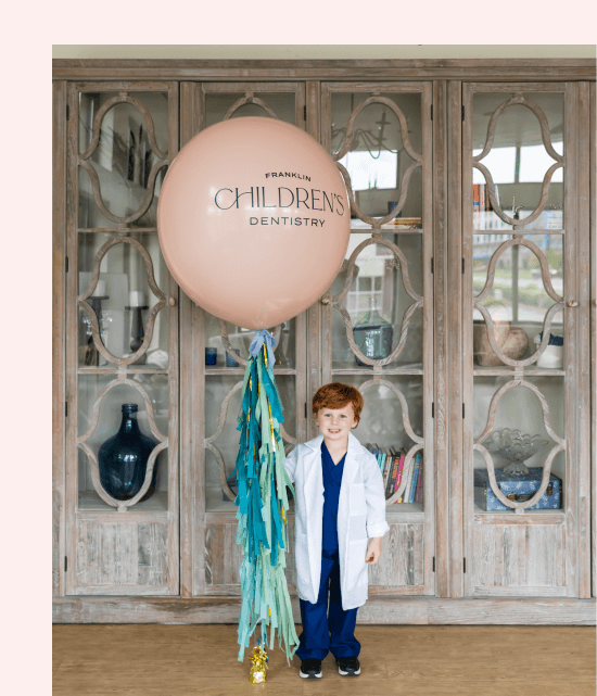 Dr. Robyn's son smiling while holding a balloon